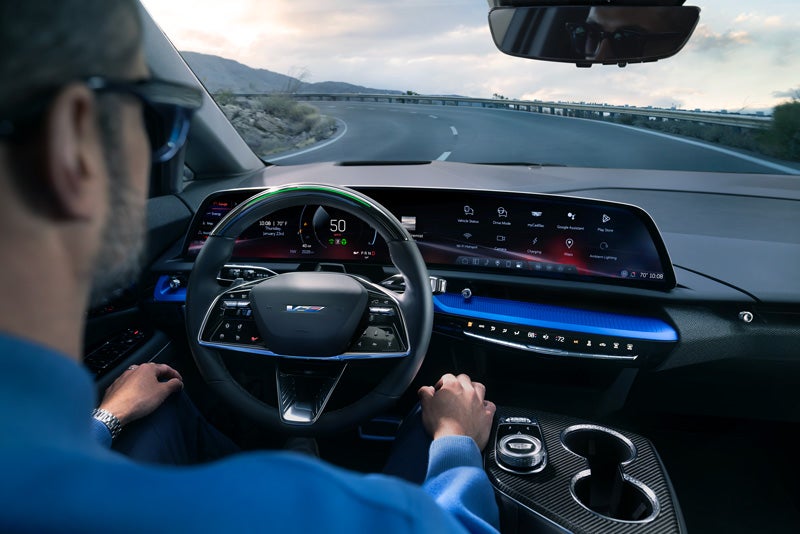 Front View of the 2026 OPTIQ-V Driving Through the Dusk Utilizing its Headlights | Landmark Cadillac in Springfield IL