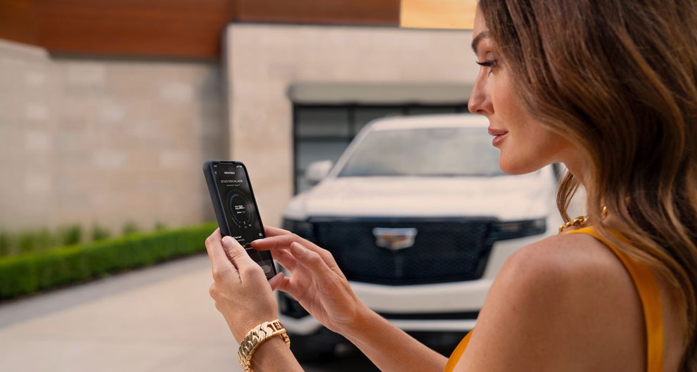 lady checking her mobile with a Cadillac vehicle background | Landmark Cadillac in Springfield IL